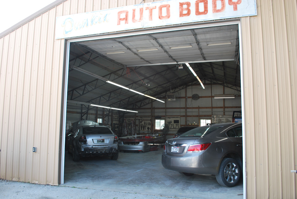 A view from outside looking in a tan shed with cars inside.